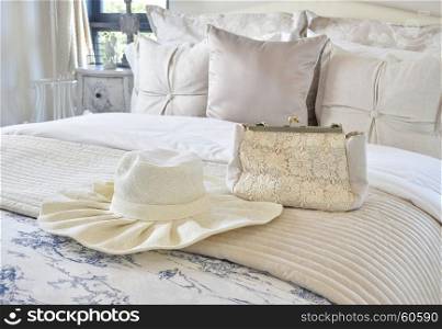 Decorative set with vintage bag and hat on bed in luxury bedroom interior