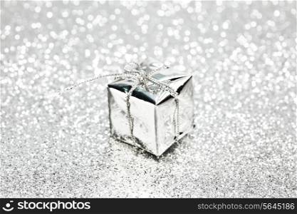 Decorative silver box with holiday gift on shiny glitter background