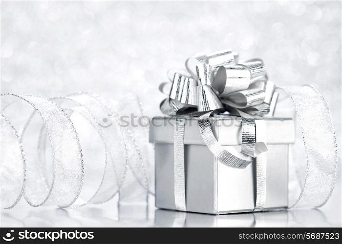 Decorative silver box with holiday gift on shiny glitter background