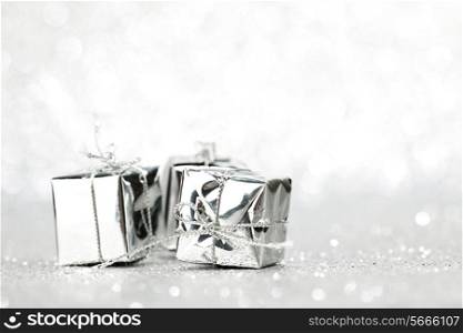 Decorative silver boxes with holiday gifts on shiny glitter background