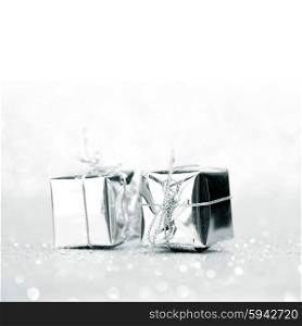 Decorative silver boxes with holiday gifts on shiny glitter background