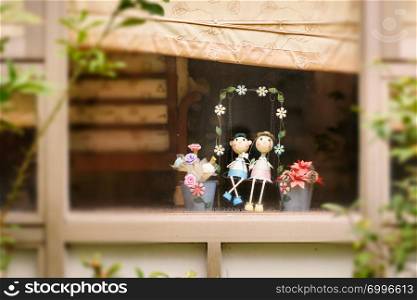 Decorative smiling toys on swings behind the window glass