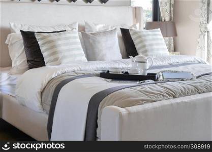 Decorative tray with book and elegant tea set on the bed in modern bedroom