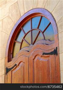 Decorative window in a wooden frame with sandstone walls