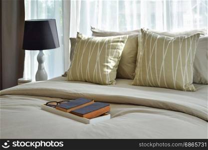 decorative wooden tray with books and striped pillows in stylish bedroom interior