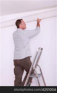 Decorator fitting coving to a ceiling