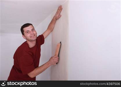 Decorator smoothing down wallpaper with a brush