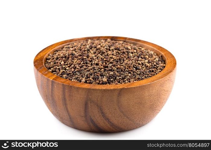Decorticated cardamom seeds in a dark stone bowl on white background