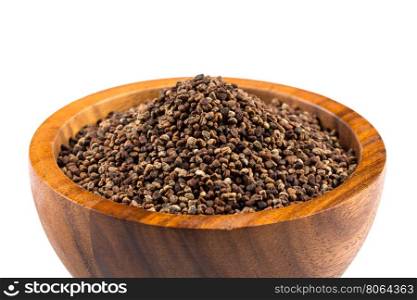 Decorticated cardamom seeds in a dark stone bowl on white background