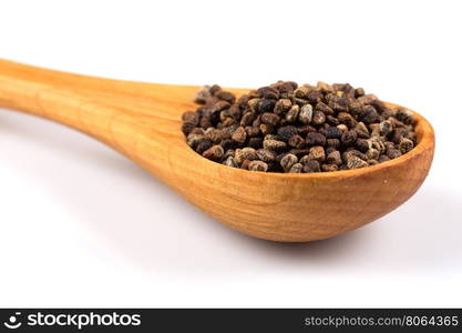 Decorticated cardamom seeds in a wooden spoon on white background