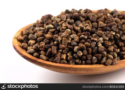 Decorticated cardamom seeds in a wooden spoon on white background