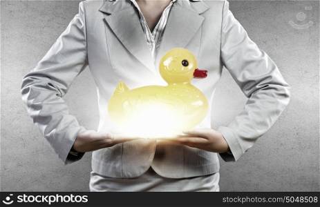 Decoy duck. Businesswoman holding in hands yellow toy rubber or plastic duck