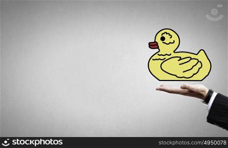 Decoy duck. Hand holding yellow toy rubber or plastic duck