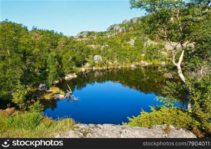 Deep blue small mountain Norway lake with rocky shore