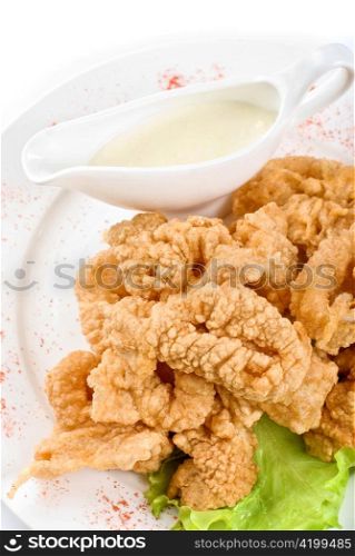 Deep-fried squid with salad leaves, sauce, on a white