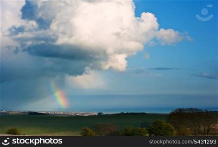 Deep rainbow over ocean with moody sky and cloud formation