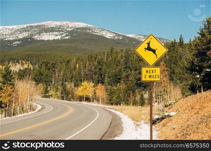 Deer crossing sign on highway at autumn sunny day in Colorado, USA. 