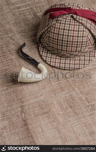 Deerstalker or Sherlock Hat and Tobacco pipe on Old Wooden table.