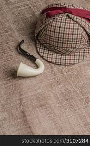 Deerstalker or Sherlock Hat and Tobacco pipe on Old Wooden table.