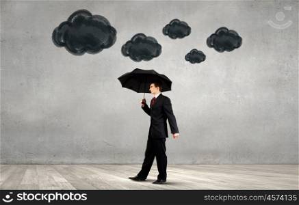 Defend your business. Businessman standing with umbrella under cloud concept