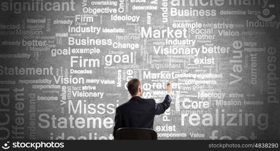 Define goals and mission. Rear view of businessman writing leadership conceptual words on wall