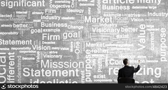 Define goals and mission. Rear view of businessman writing leadership conceptual words on wall