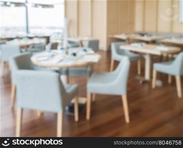 Defocus of modern restaurant of hotel with wooden furniture and view of river