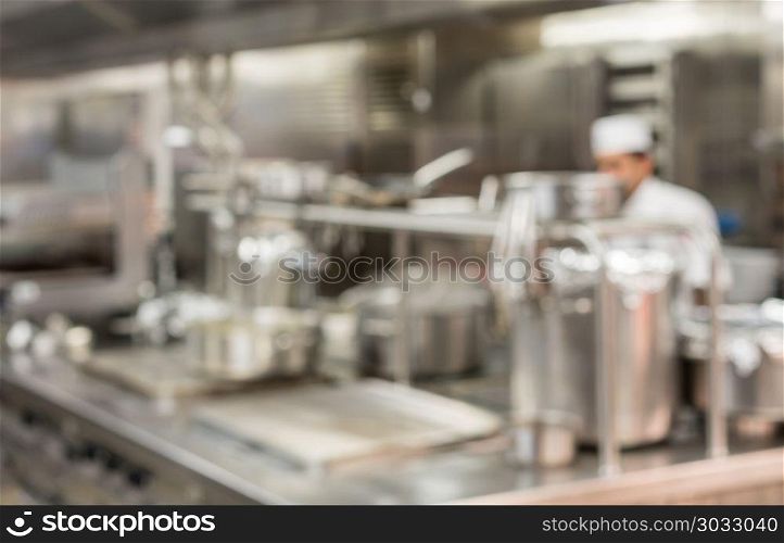 Defocused chef preparing food in commercial kitchen. Defocused chef preparing food in commercial stainless steel kitchen in restaurant. Defocused chef preparing food in commercial kitchen