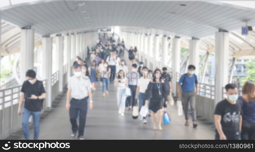 Defocused crowd wearing medical masks for virus protection and walking in walkway, blurred background, coronavirus, china covid-19 virus epidemic, pandemic, outbreak and air pollution concept