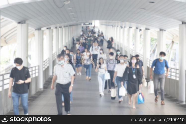 Defocused crowd wearing medical masks for virus protection and walking in walkway, blurred background, coronavirus, china covid-19 virus epidemic, pandemic, outbreak and air pollution concept