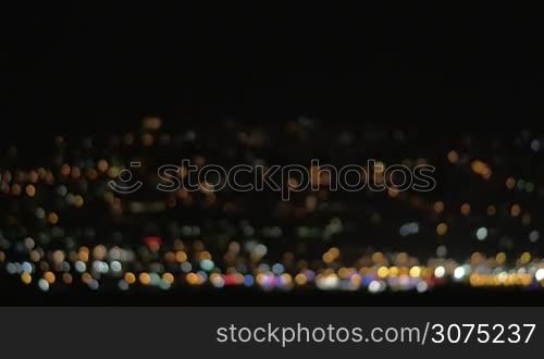 Defocused loop video of colorful city lights at night. Multicolor twinkling dots on black background. Can be used as background