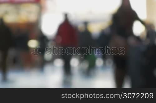 Defocused shot of crowd of people at the station. They walking indoor against bright light
