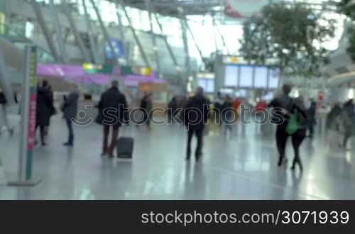 Defocused shot of people and passengers walking in light big modern airport hall