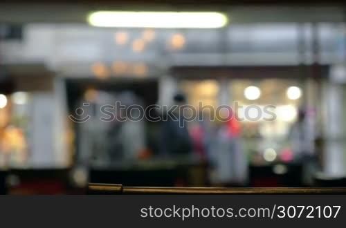 Defocused shot of people walking along the street, view through the cafe or restaurant window