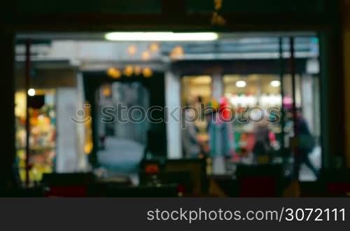 Defocused shot of people walking by the restaurant show window. Video is made inside the restaurant.