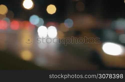 Defocused shot of transport traffic on wet road in night city