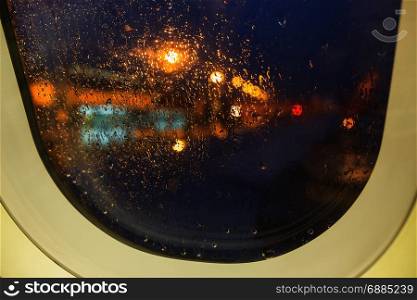 defocused view on airplane wing through passenger window with rain drop