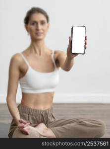 defocused woman home doing yoga holding smartphone