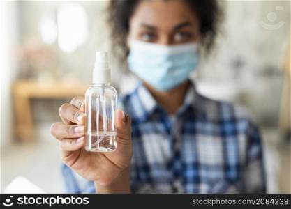 defocused woman with medical mask holding hand sanitizer