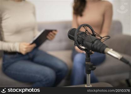 defocused women doing radio interview with microphone