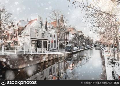 Delft Netherlands Houses and Canal in residential district view at winter snowstorm. Pastel trendy toning. Beautiful inspiring moody faded scenery