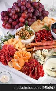 Delicacy assorted appetizer platter of salami and cheese, grissini wrapped in Parma ham, olives and citrus fruits. An original antipasto serving for a party.