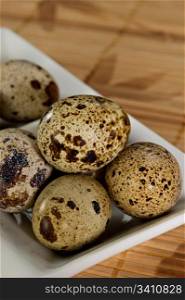 Delicate, beautiful Quail Eggs in a white bowl on a bamboo mat. Shallow dof.