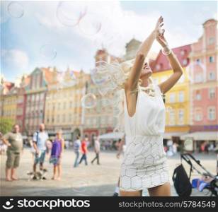 Delicate blond woman catching flying soap bubbles