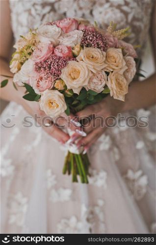 Delicate bouquet of flowers in womens hands.. A girl in a chic white dress holding a bouquet of flowers 1965.