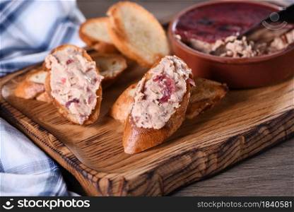 Delicate chicken pate with mashed cranberries spread on toasted baguette slices. Country style food.