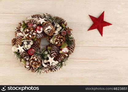 Delicate Christmas wreath of pine cones and a red star on gray wooden background