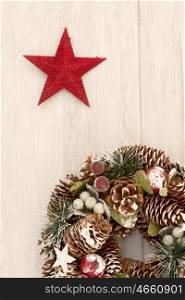 Delicate Christmas wreath of pine cones and a red star on gray wooden background