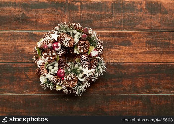 Delicate Christmas wreath of pine cones on wooden background