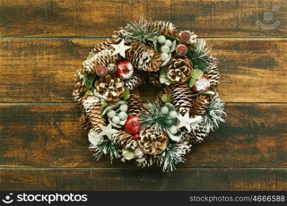 Delicate Christmas wreath of pine cones on wooden background